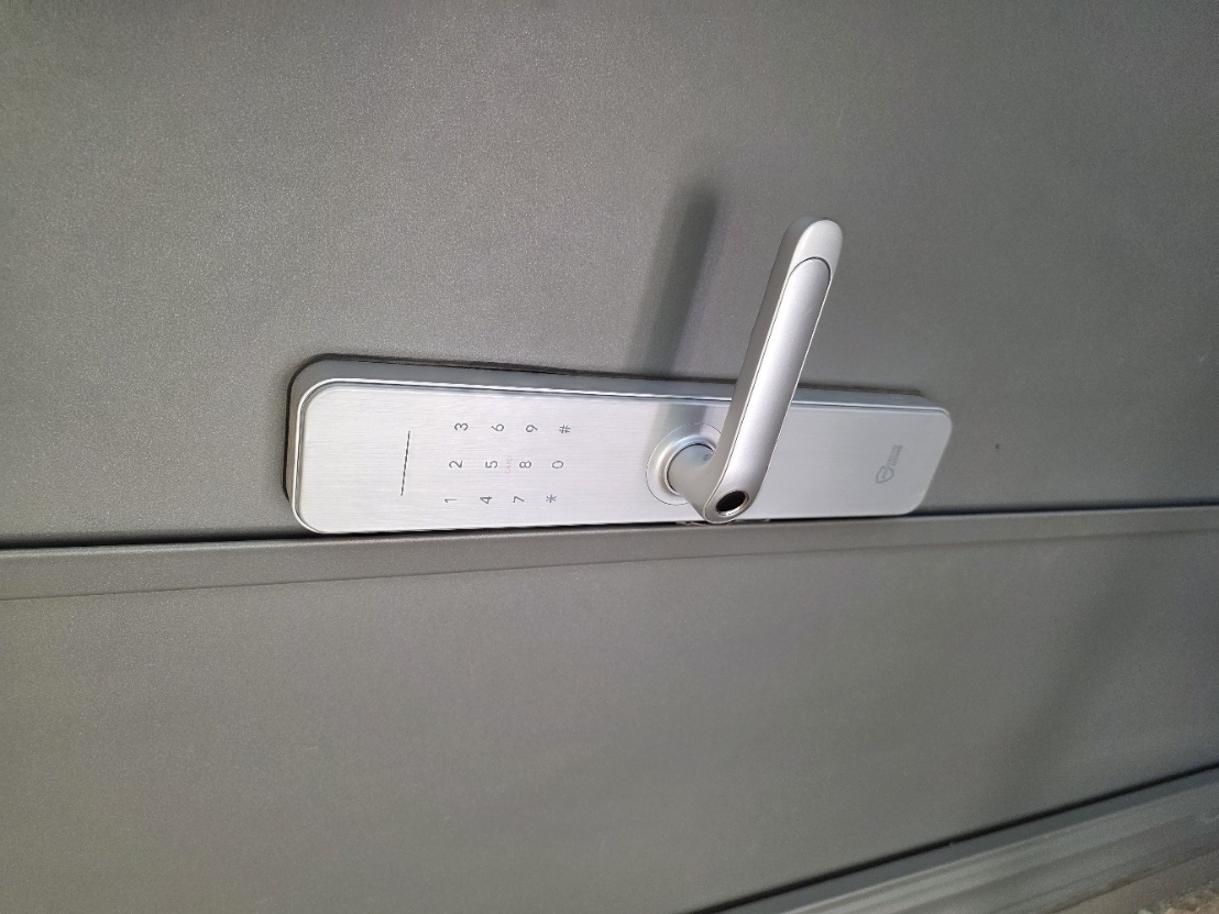 Silver front-door keypad with number keys and a number sign key above the door handle.