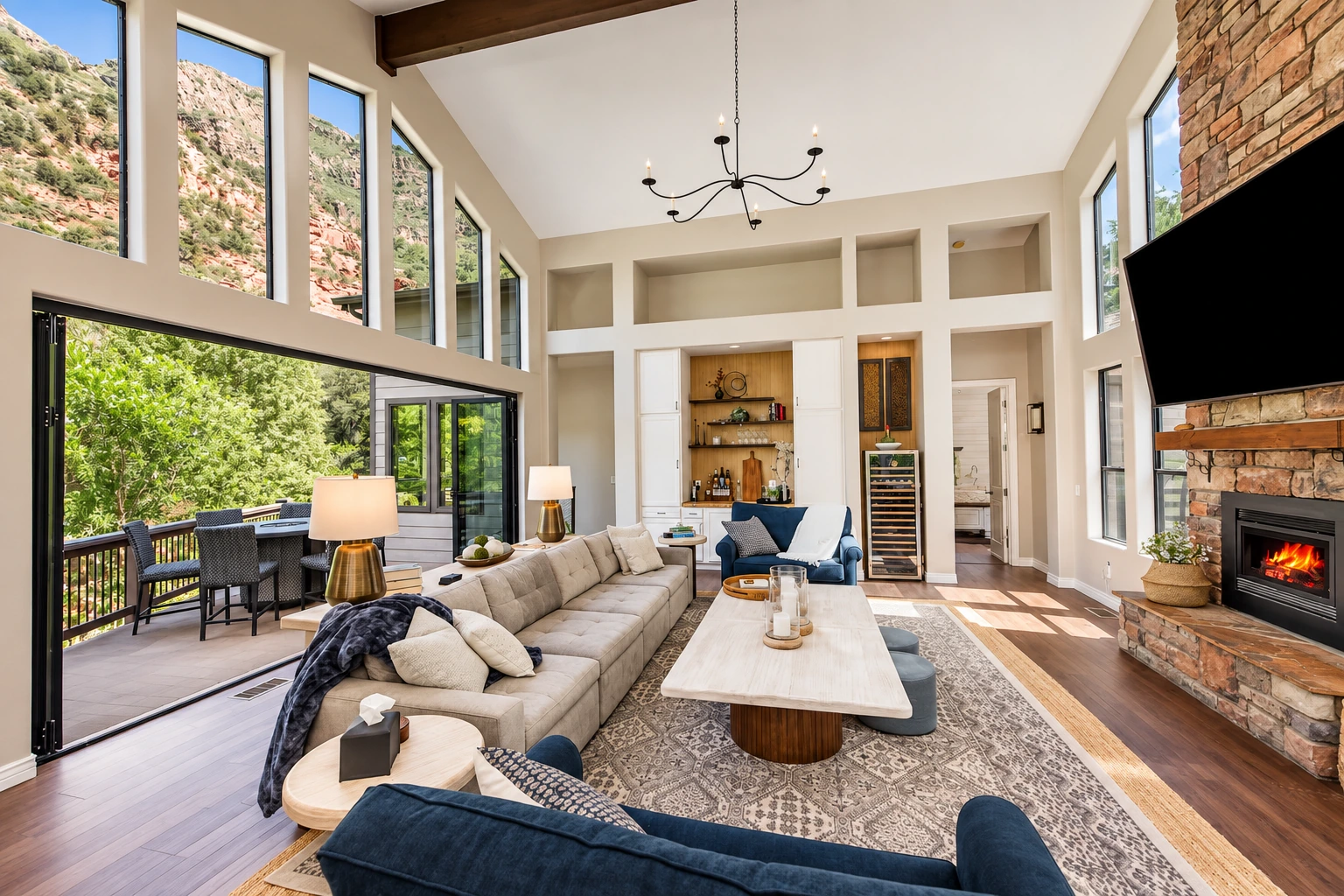Sunlit living room with canyon views, open doors to the deck, and a stone fireplace