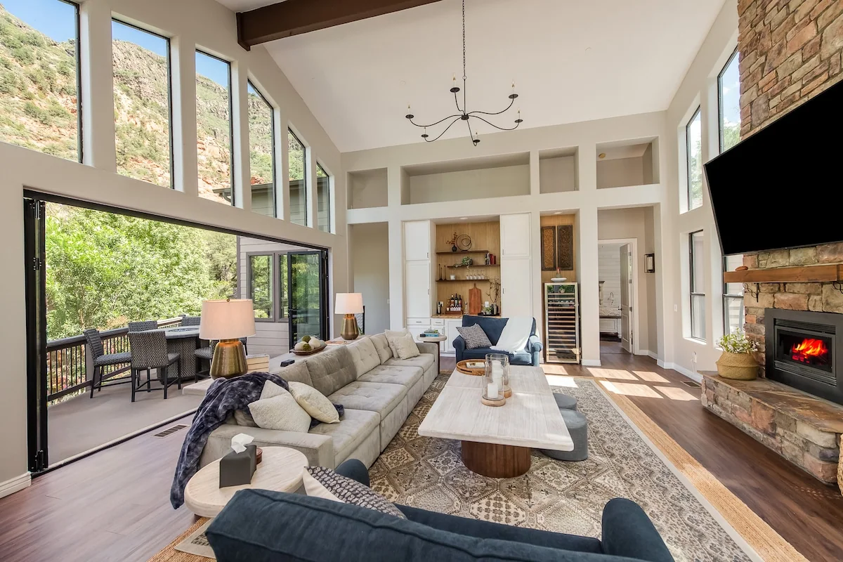 Open living area framed by tall windows and greenery