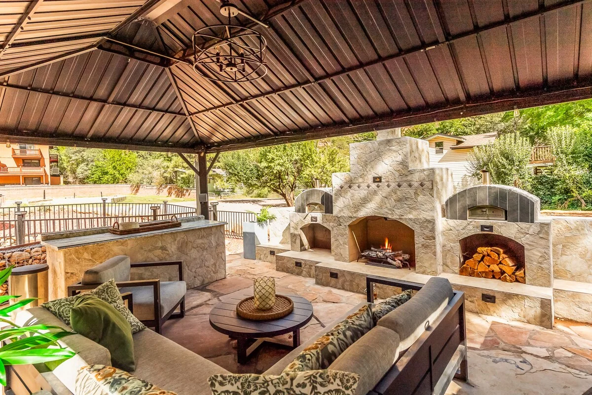 Covered outdoor lounge with seating and a fireplace